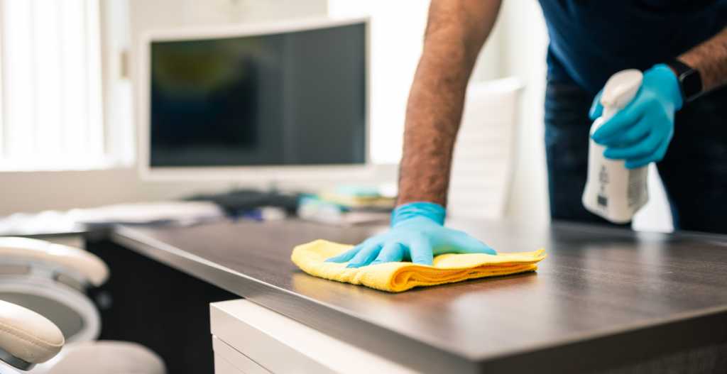 Man disinfecting an office desk